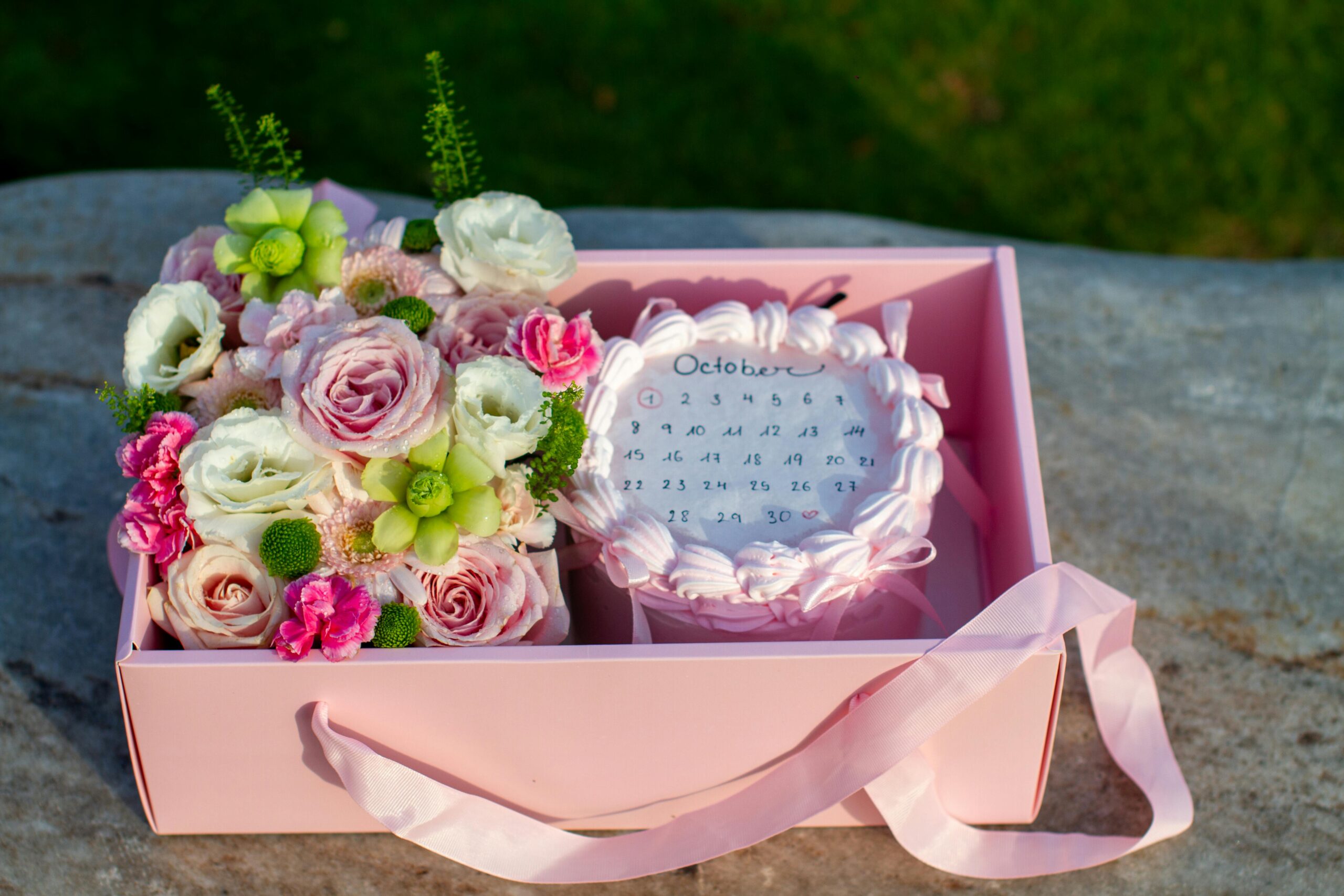 Elegant pink gift box with floral bouquet and October calendar for special occasion.