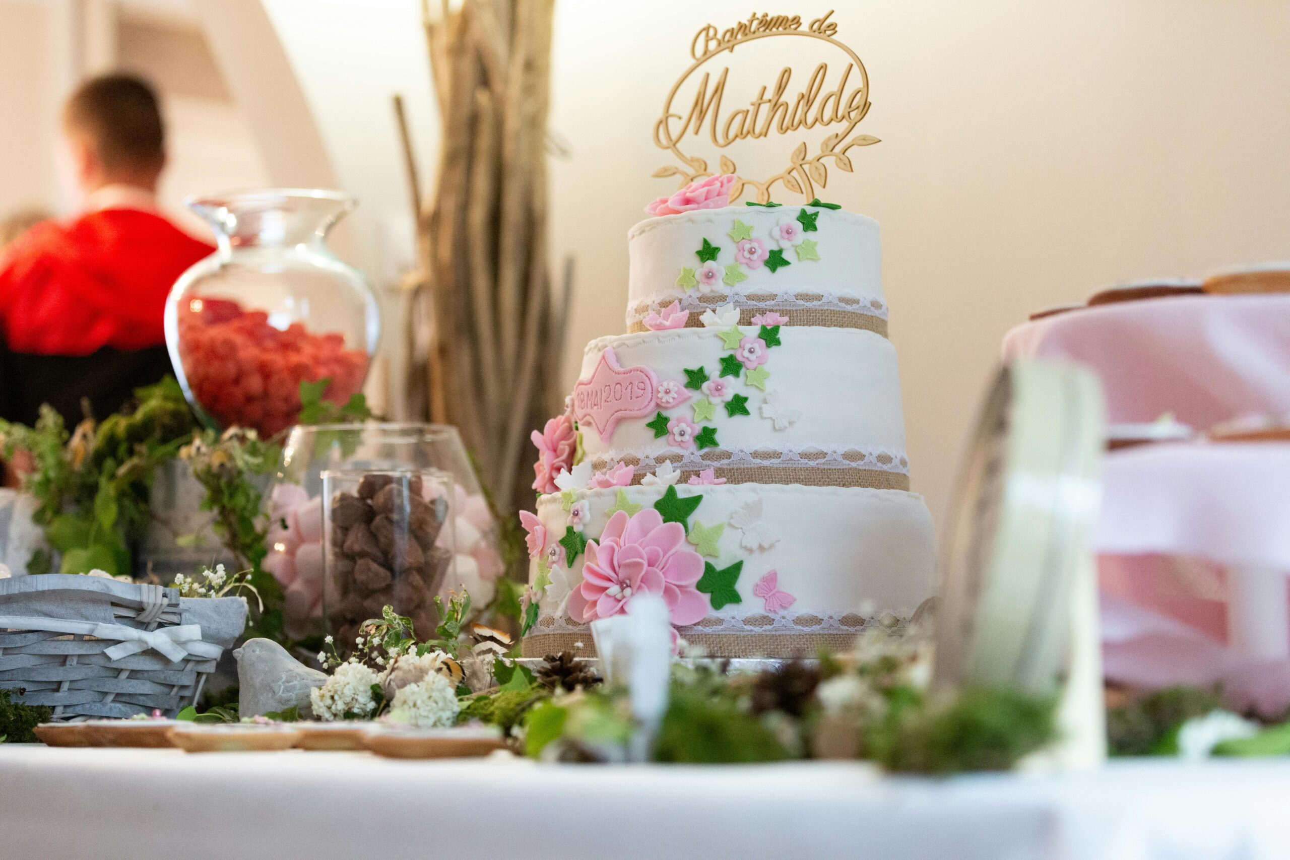 Elegant three-tiered cake with floral decor for a baptism party setting.